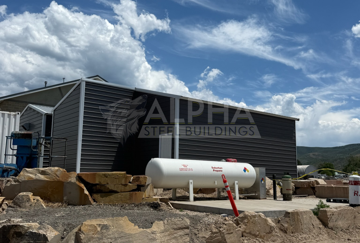 Back angled side exterior view of a 24'x30'x12' vertical roof steel utility building with a 12'x10' attached lean-to, enclosed side walls, and vertical roof metal panels.