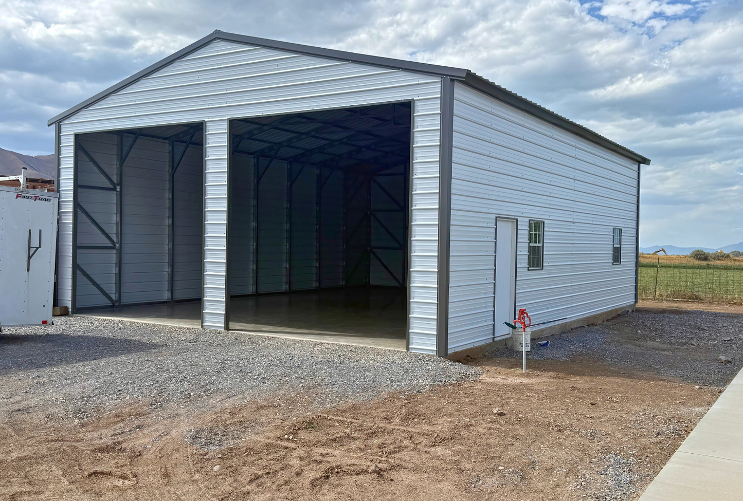 30x40x13 A-frame steel building with vertical roof, (2) 12' x 12' overhead door frame outs on the end, (1) 36" x 80" walk-in door on the side, (2) 30" x 36" windows on the side, sides & ends diagonal bracing, front right angled view.