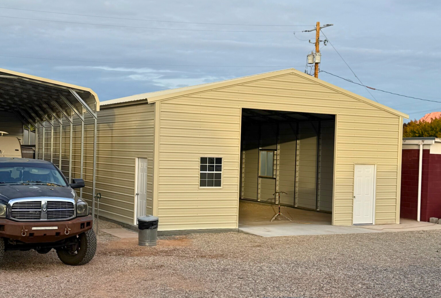 Front left angled view of a 30x45 A-frame steel building with vertical roof, closed sides and ends, 12x12 overhead door frame-out, windows, and walk-in doors.