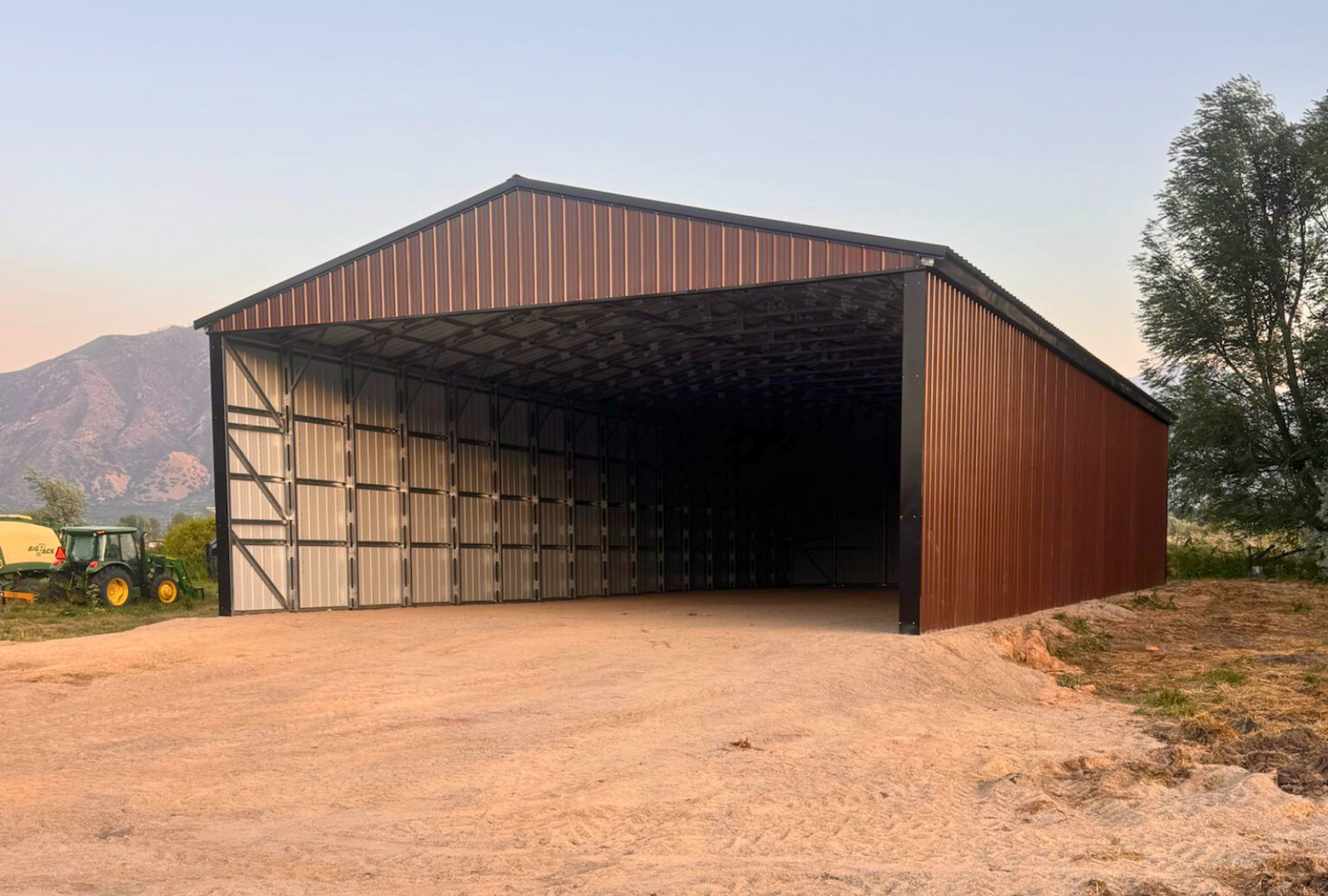 Outside front right view of 36'x80'x14' steel hay shop features ladder style truss design, vertical roof, 14 Ga. frame, 40PSF ground snow load, both sides, back end & front gable end enclosed with vertical siding, lateral & back end diagonal bracing.
