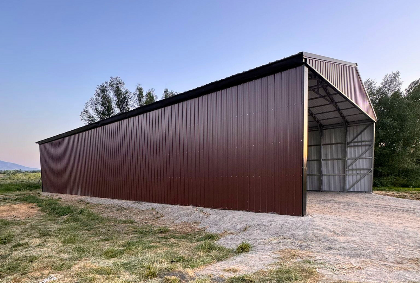 Outside front left view of 36'x80'x14' steel hay shop features ladder style truss design, vertical roof, 14 Ga. frame, 40PSF ground snow load, both sides, back end & front gable end enclosed with vertical siding, lateral & back end diagonal bracing.