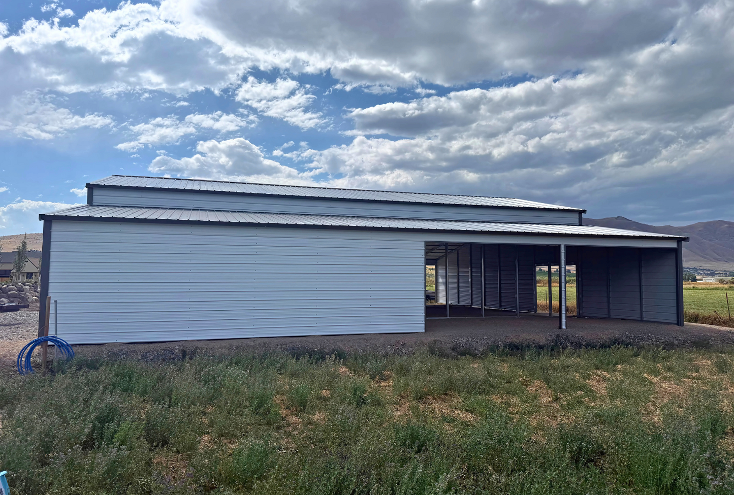 60'x60'x14' down to 12'-9' steel barn style with lean-tos, two panels under the eave, both sides closed, all ends closed, with 12' x 15' wash bay, (1) 12' x 13' frame out on the end, (1) 9' x 7' frame out on the end, (1) 14'2" x 12' wash bay frame out on the side, (4) 9'2" x 8' stall frame outs on the side of left lean-to, (2) 14'2" x 8' frame outs on the side of right lean-to, (1) 36" x 80" walk-in door, right side view.