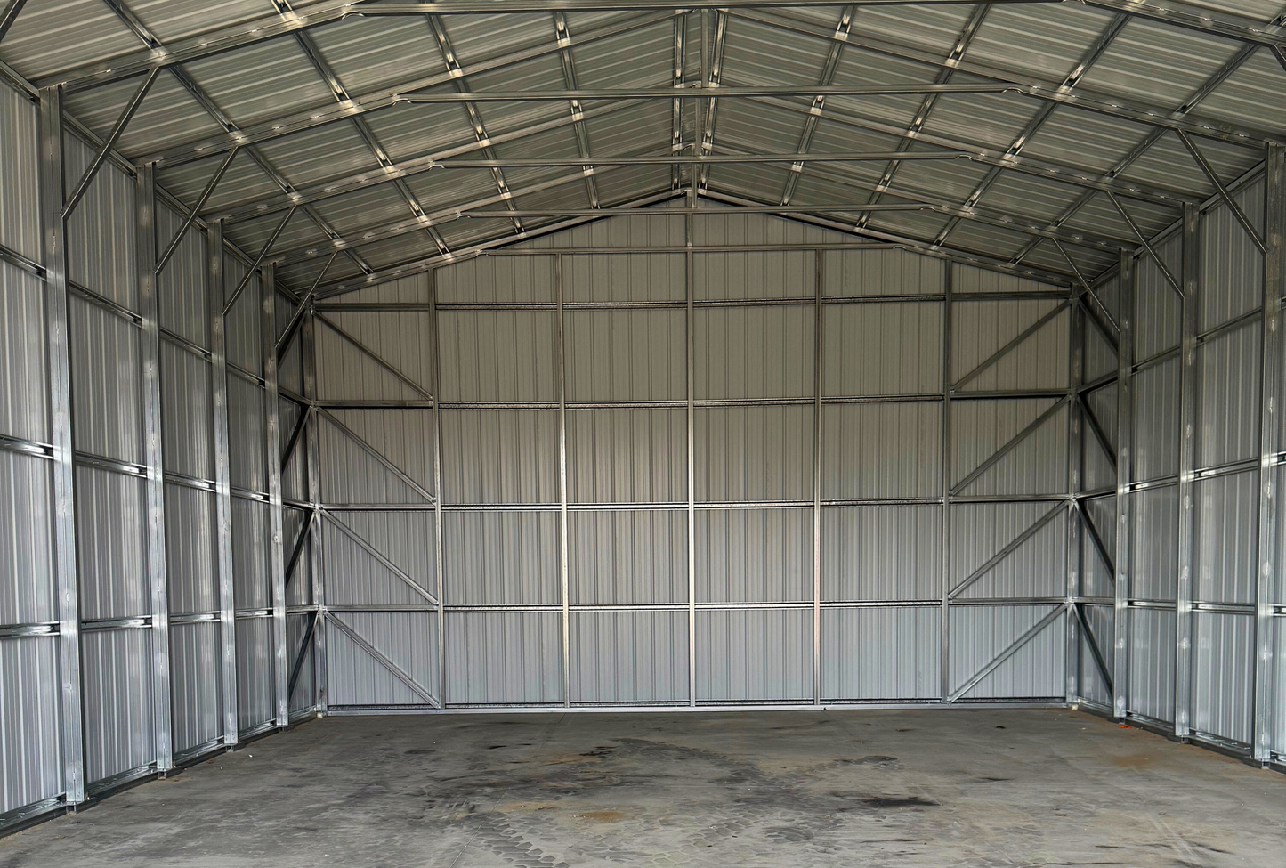 Interior view facing back of 30x45x16 steel building with enclosed walls and double leg post supports.