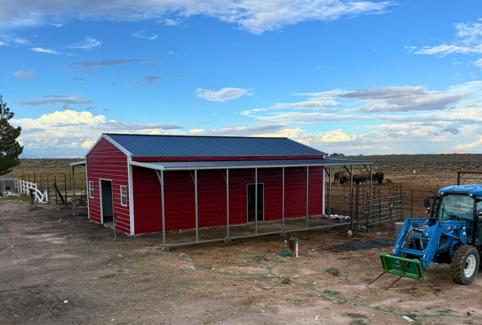 Front right angle view of a 48x40 metal barn by Alpha Steel Buildings featuring dual 12-foot lean-tos, vertical roof, two 7x8 overhead door frame-outs, and 4x8 sliding doors on each side.