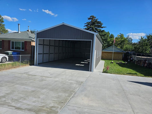 22'x48'x12' A-frame vertical roof garage with 14 Ga. frame, 40PSF ground snow load, fully enclosed, featuring one 6' x 6' roll-up door on back end, four 30" x 36" windows, one 36" x 80" walk-in door, one 20' x 10' overhead door frame out on front end, and thirty-eight 1/2" concrete bolts.