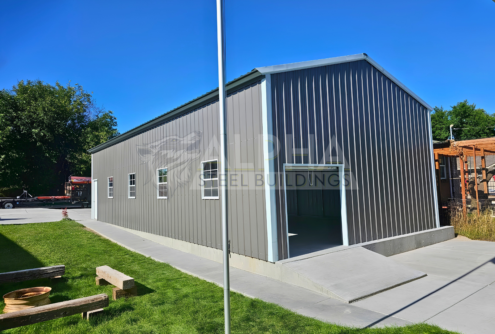 Rear view of 22' x 50' x 12' steel garage featuring a 20' x 10' overhead door frame out, one 6' x 6' roll-up door on the back, four windows and one walk-in door.