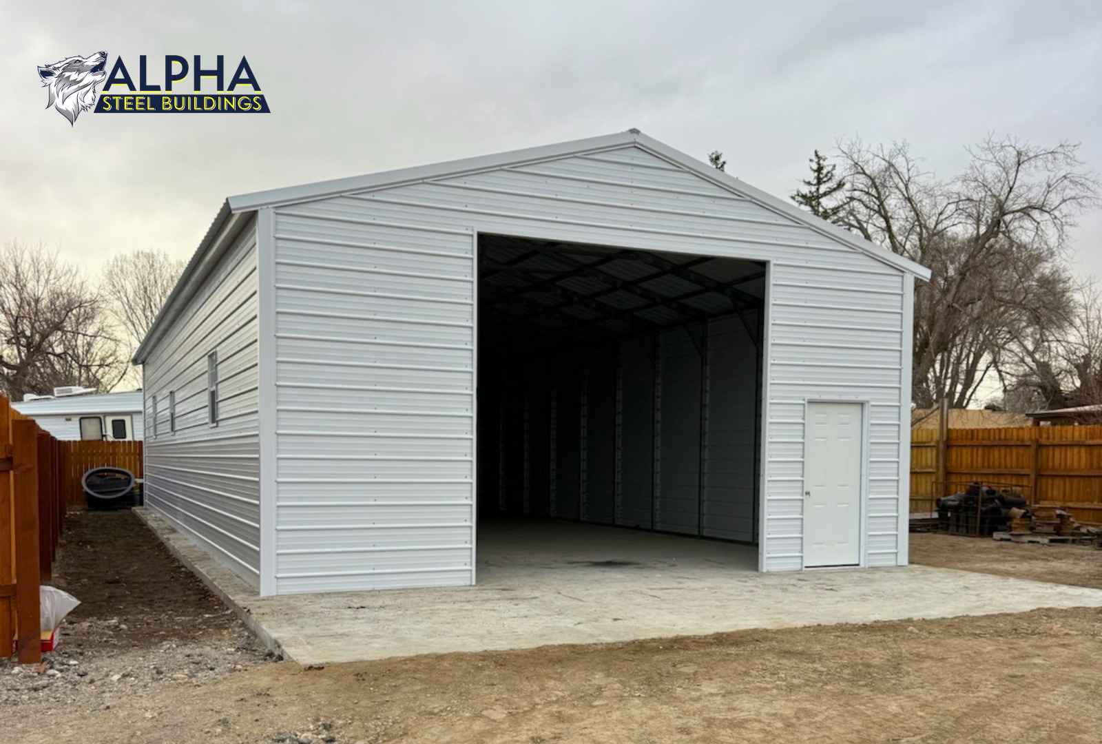 Front left angled view of 26x60x12 A-frame steel garage with vertical roof, enclosed sides and ends, windows, a framed overhead door opening and a 36" x 80" walk-in door.