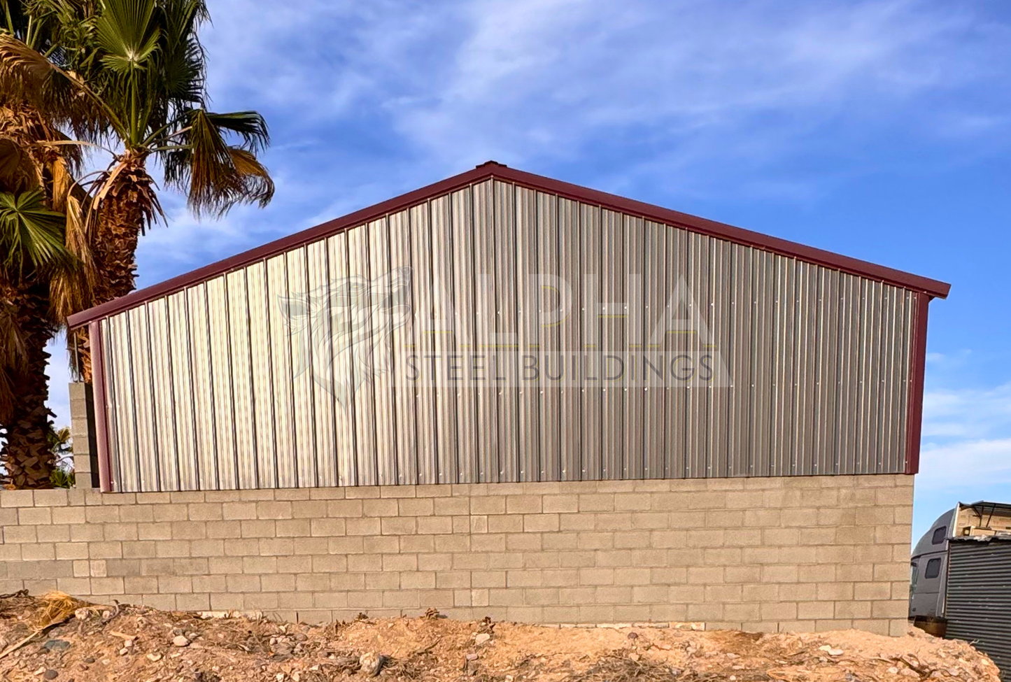 Rear view of a 30x35x6 A-frame steel agricultural building showing the fully enclosed rear end with vertical metal panels above the existing block wall.