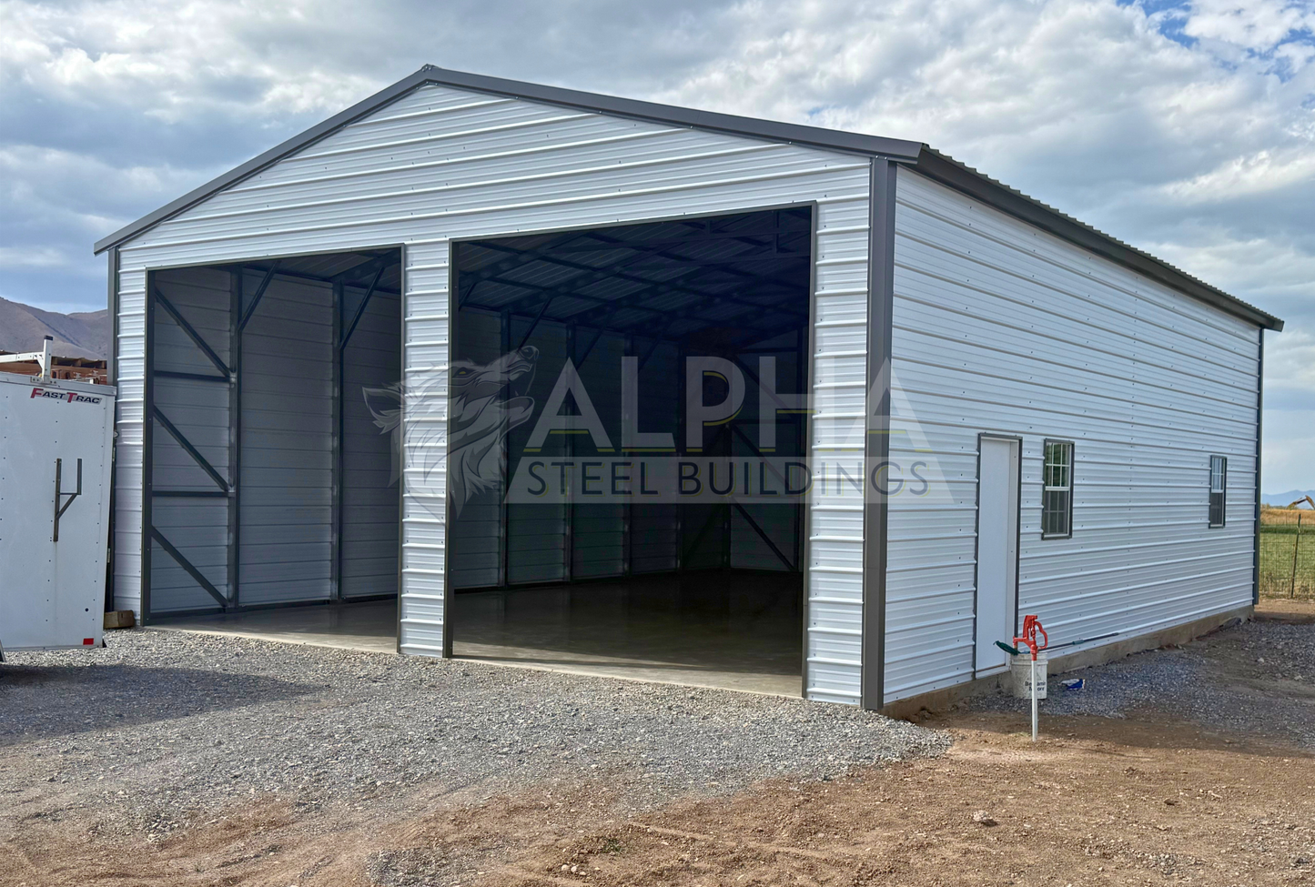 30x40x13 A-frame steel building with vertical roof, two 12x12 overhead door frame-outs, walk-in door and windows, front right angled view