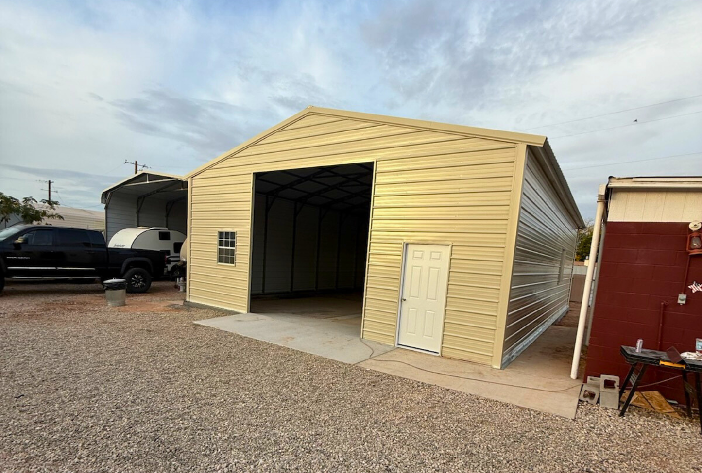 Front right angled view of a 30x45 A-frame steel building featuring vertical roof, closed sides and ends, 12x12 overhead door frame-out, windows, and walk-in doors.