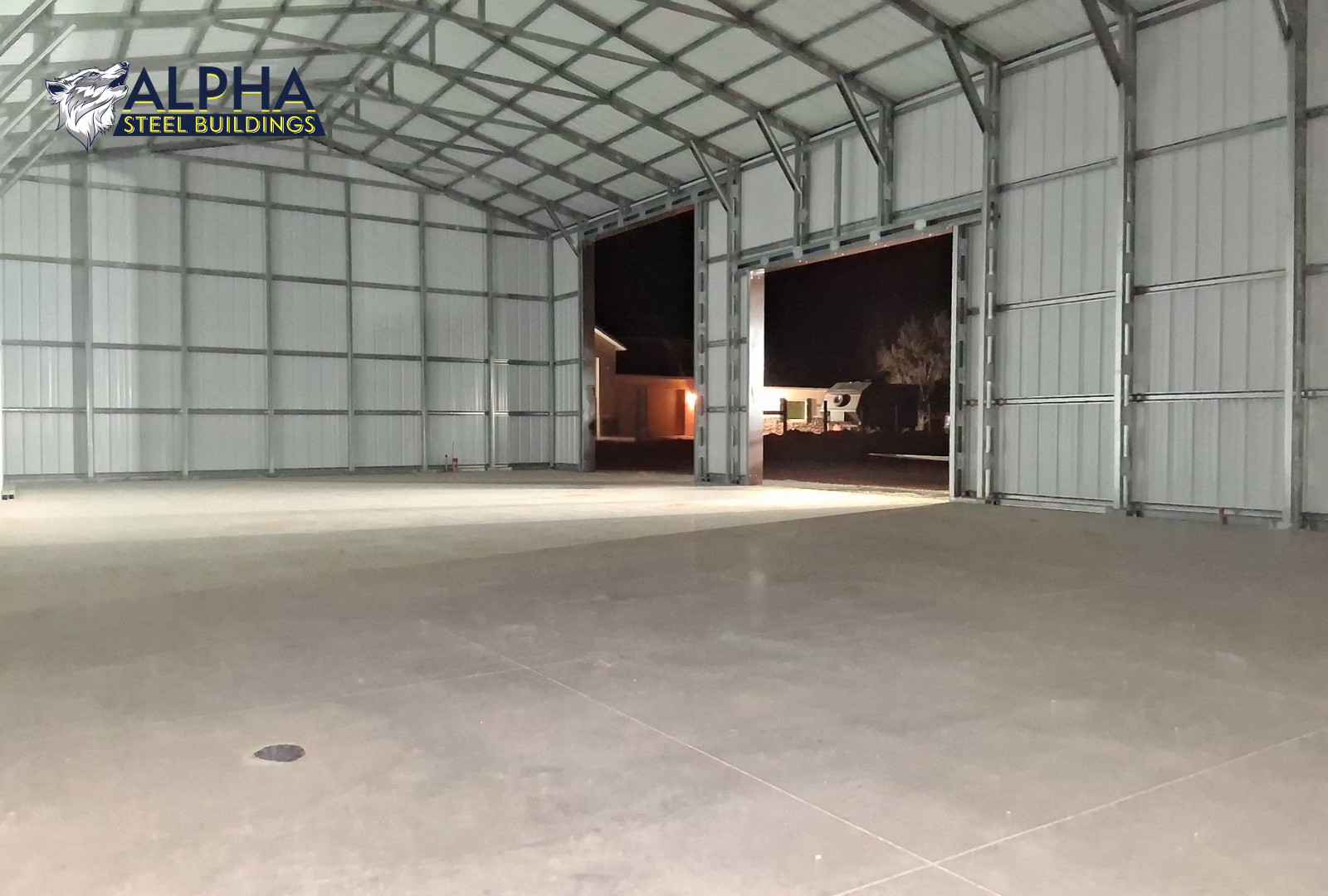 Interior angled view inside 30x60x15 steel garage looking from front to back, showing vertical roof panels, framing, and side wall openings.