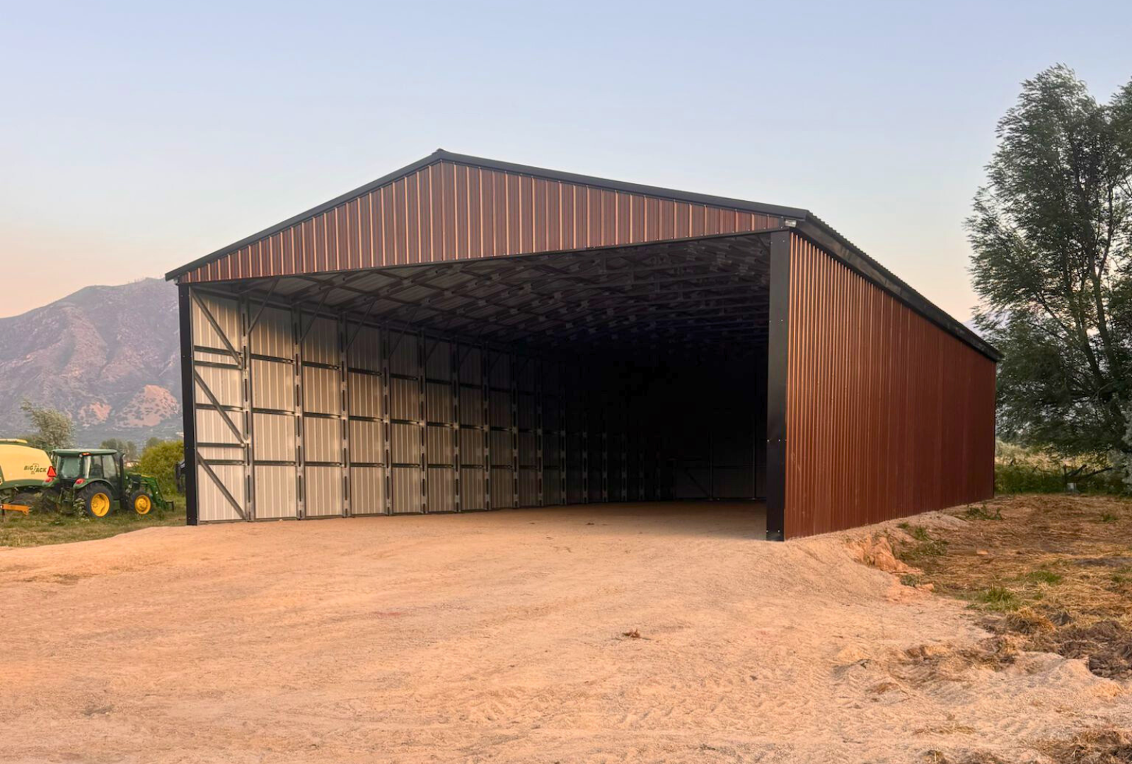 Outside front right view of 36'x80'x14' steel hay shop features ladder style truss design, vertical roof, 14 Ga. frame, 40PSF ground snow load, both sides, back end & front gable end enclosed with vertical siding, lateral & back end diagonal bracing.