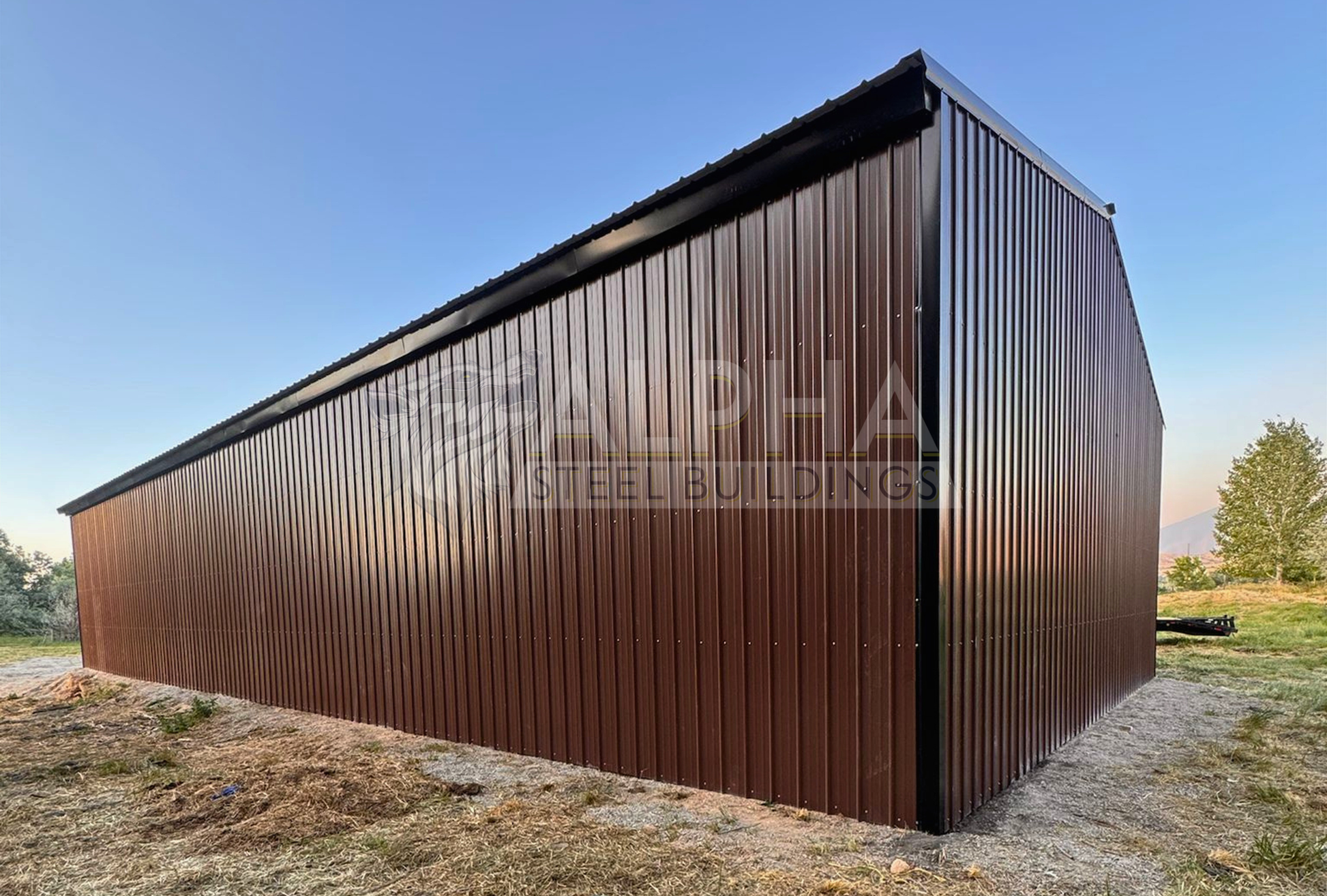 Rear left angle view of a 36x80x14 steel agricultural building showing the enclosed side and back end with vertical metal panels and a vertical roof.