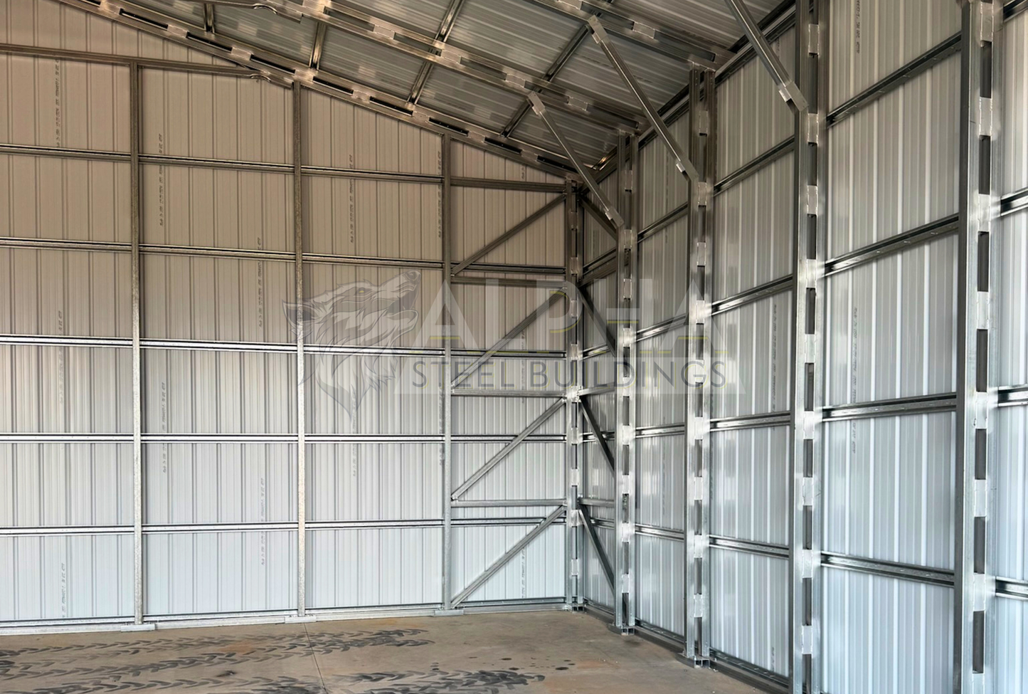 Internal right angle view of 40'x40'x15' steel shop features ladder style truss design, vertical roof, fully enclosed with vertical siding, one 36" x 80" walk-in door, and two 12' x 14' overhead door frame outs on the end. 