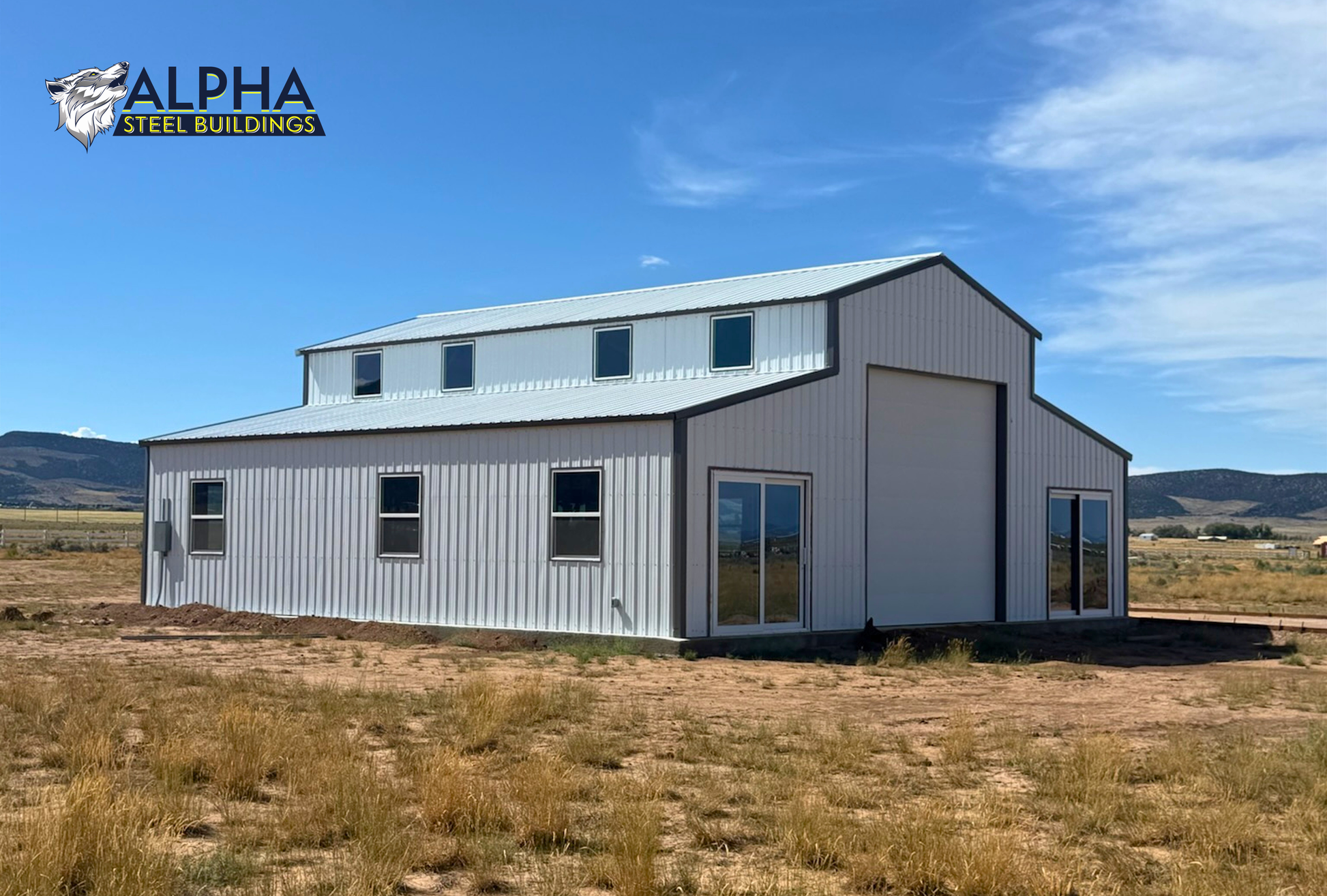 Front corner view of a 44'x45' barn style steel building featuring a vertical roof, enclosed lean-to sections, multiple windows, glass entry doors, and a 14' overhead garage door.