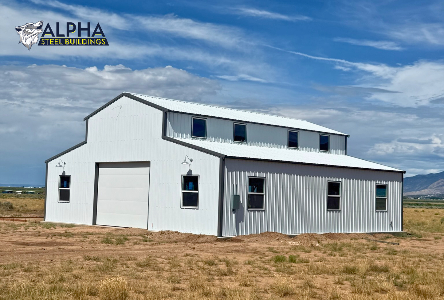 Rear corner view of a 44'x45' barn style steel building with a vertical roof, enclosed lean-to sections, multiple windows, and a 14' overhead garage door.