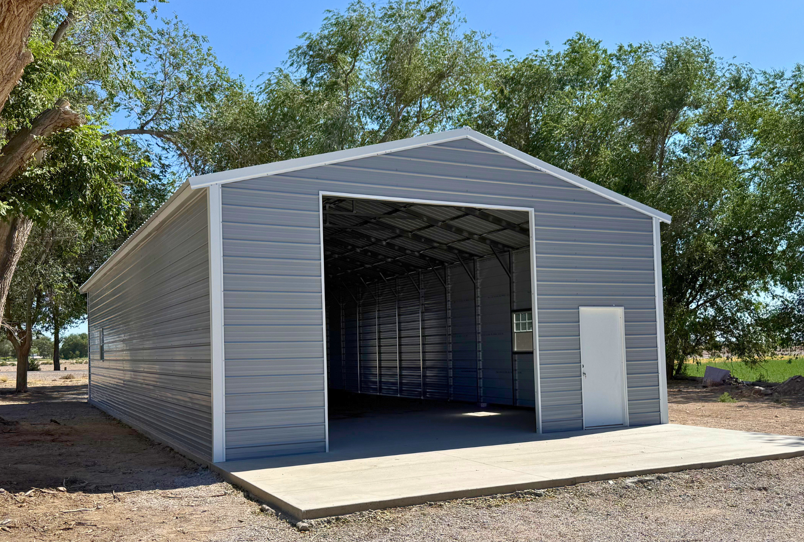 26x60x12 A-frame steel building with vertical roof, (1) 12' x 12' overhead door frame out on the end, (1) 10' x 10' overhead door frame out on the end, (1) 36" x 80" walk-in door on the side, (2) 30" x 36" windows on the side, front left angled view.