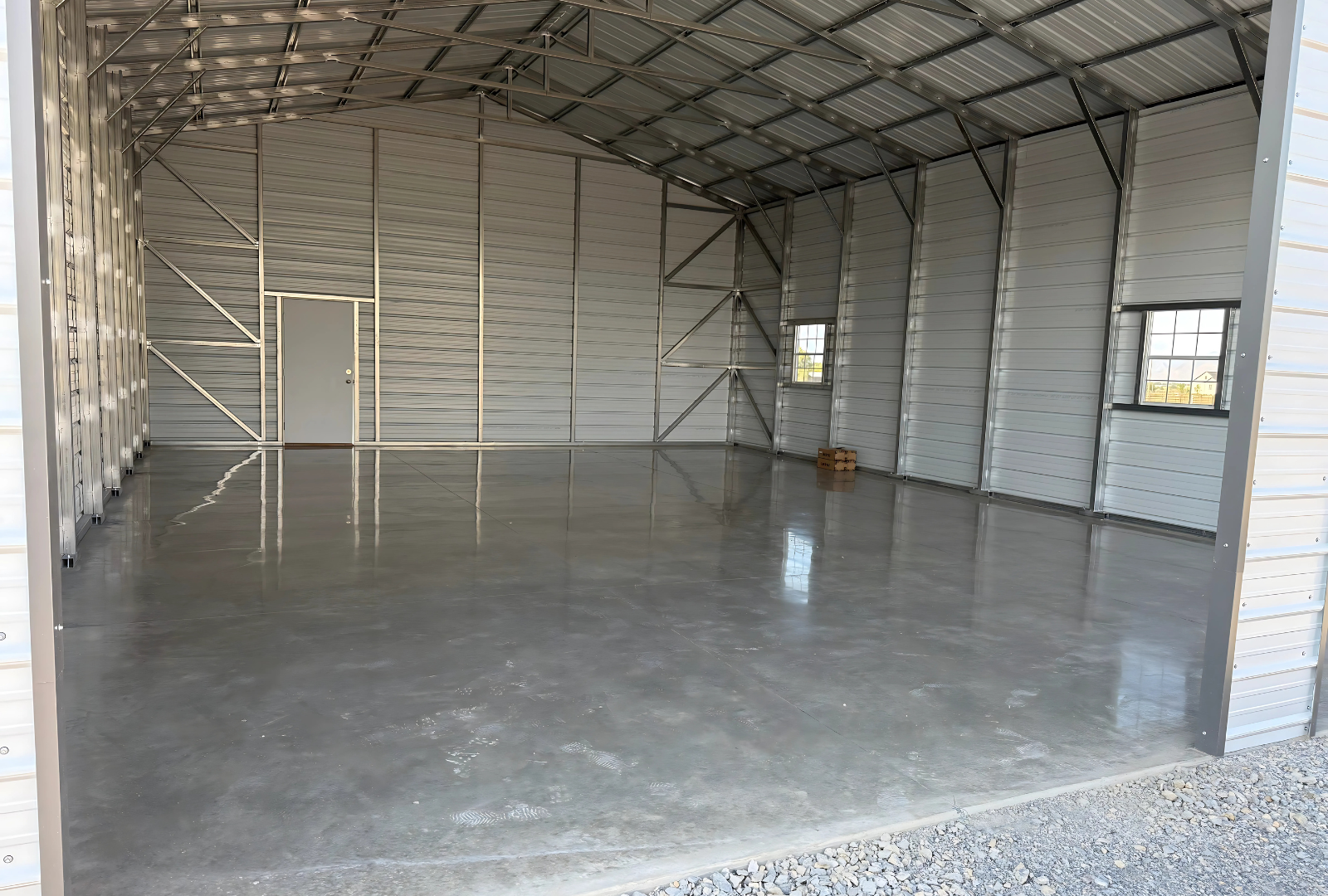 30x40x13 A-frame steel building with vertical roof, (2) 12' x 12' overhead door frame outs on the end, (1) 36" x 80" walk-in door on the side, (2) 30" x 36" windows on the side, sides & ends diagonal bracing, left inside angled view.