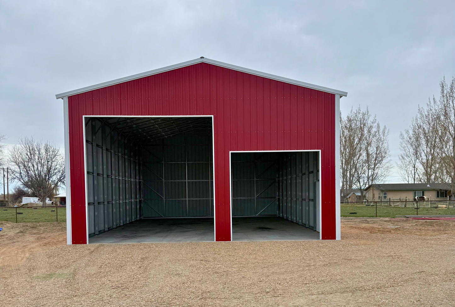 Front view of 30x45x16 A-frame steel building with vertical roof, 14' x 14' and 10' x 10' overhead door frame-outs, and walk-in door on closed vertical end.