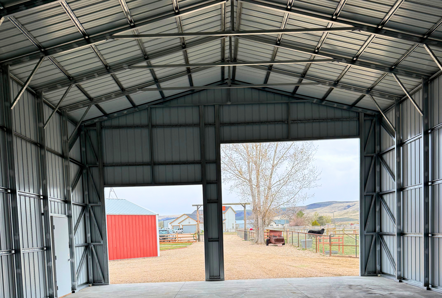 Interior view of steel building looking toward front end with visible overhead door frame-outs and structural bracing.