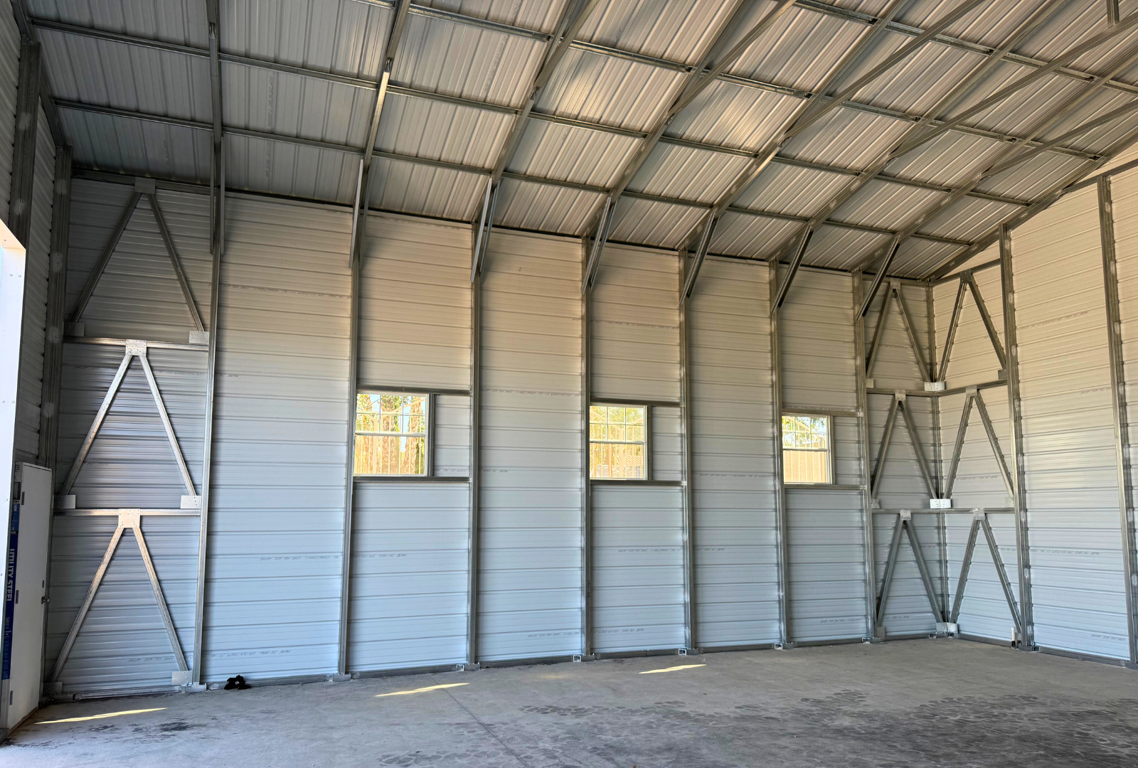 A-frame steel building, 30x35 with 16-foot height and double legs, vertical roof, enclosed sides and ends, overhead door frame-outs (12x14 and 10x12), plus walk-in doors and windows. Built with 14-gauge framing and rated for 30 PSF ground snow load, inside view.