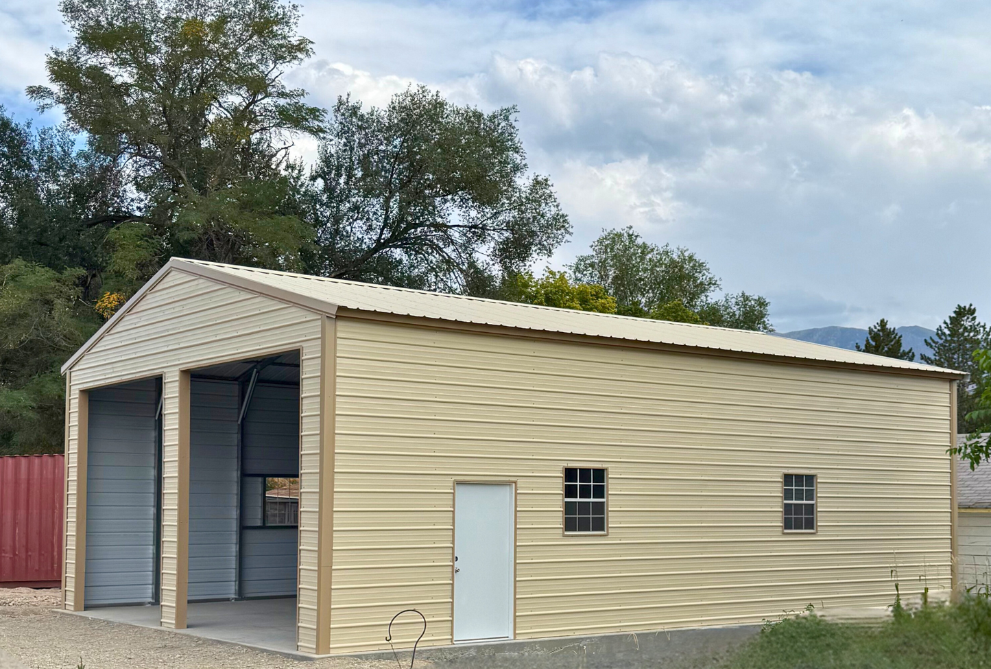 0x40x13 A-frame steel building with vertical ivory roof and saddle tan trim, enclosed sides and ends, two 12x12 overhead door frame-outs, four windows, and two walk-in doors. Built with 14-gauge framing and certified for 34 PSF snow load and 115 MPH wind load, right side angled view.