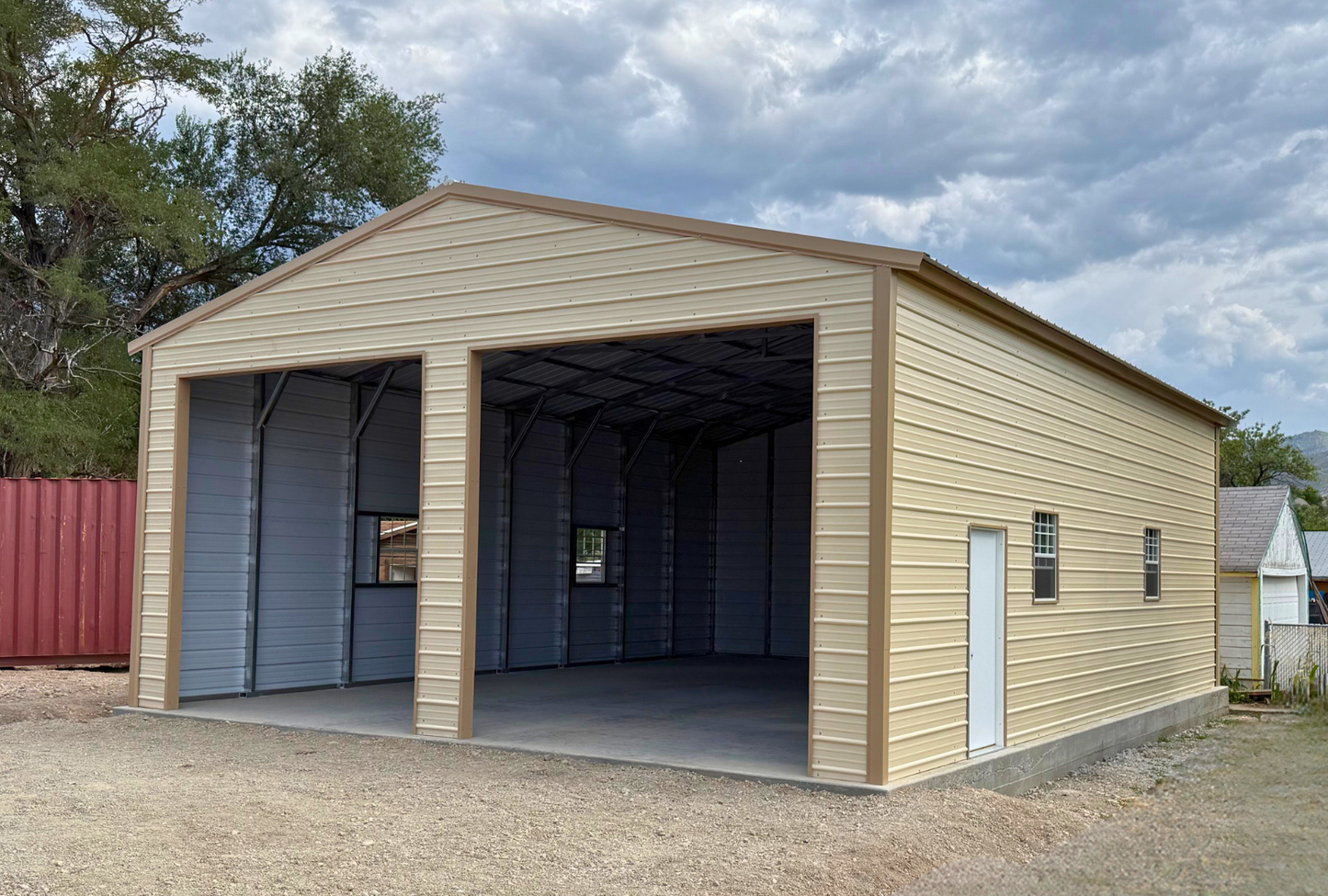 0x40x13 A-frame steel building with vertical ivory roof and saddle tan trim, enclosed sides and ends, two 12x12 overhead door frame-outs, four windows, and two walk-in doors. Built with 14-gauge framing and certified for 34 PSF snow load and 115 MPH wind load, front right side angled view.