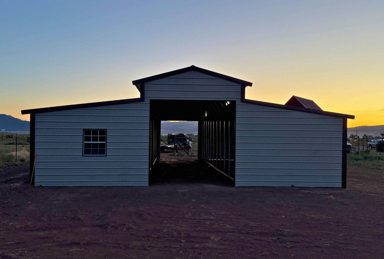 36'x60'x12' down to 10'-8' steel barn style with lean-tos, two panels under the eave, both sides closed, all ends closed, with 12' x 10' tack room, (2) 10' x 10' frame outs on the ends, (1) 10' x 10' frame out on the side of main, (4) 4' x 7' stall frame outs, (2) 30" x 36" windows, (2) 36" x 80" walk-in doors, back view.