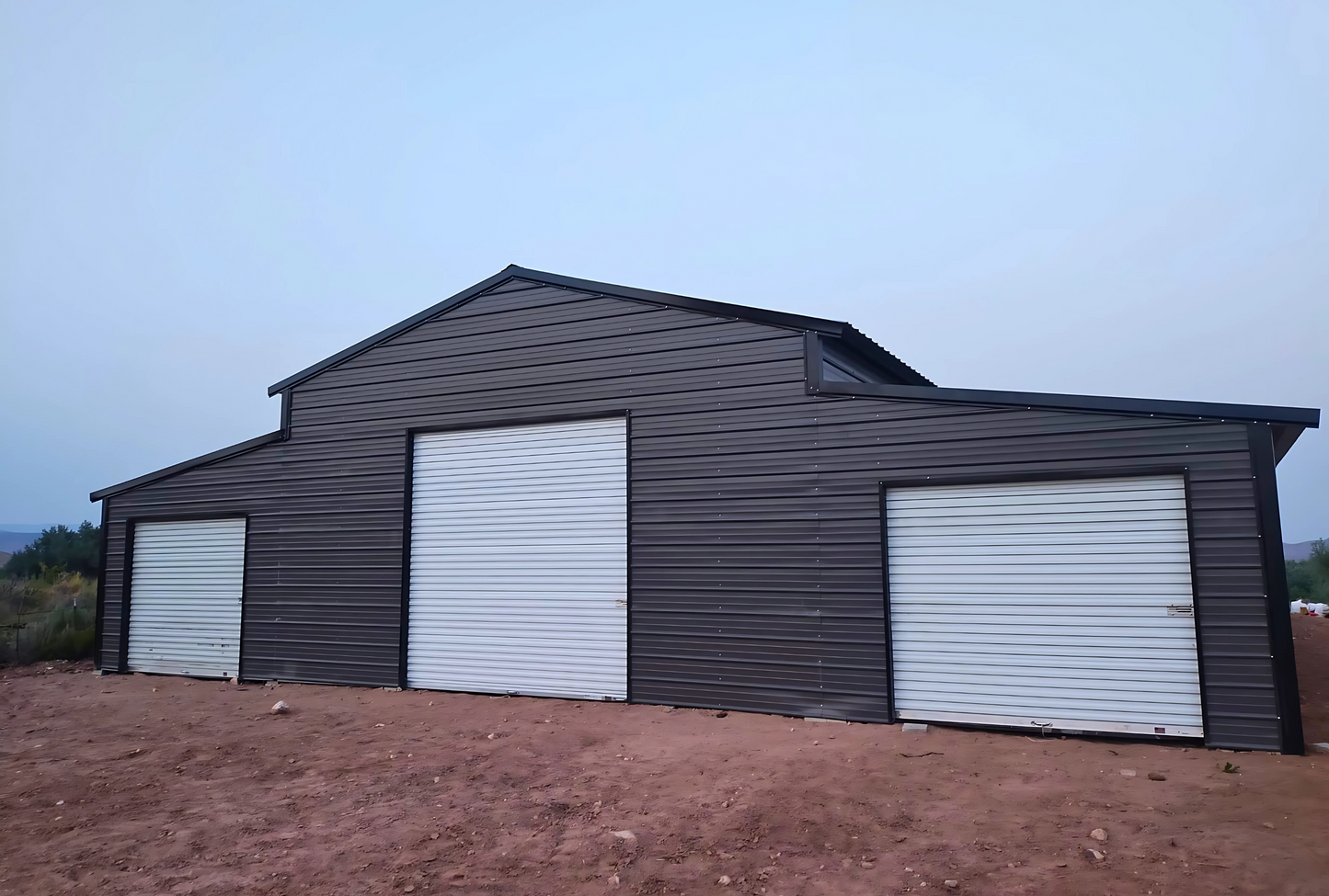 Front right view of 48' x 100' steel barn with lean-tos, and garage doors for livestock or farm equipment storage.