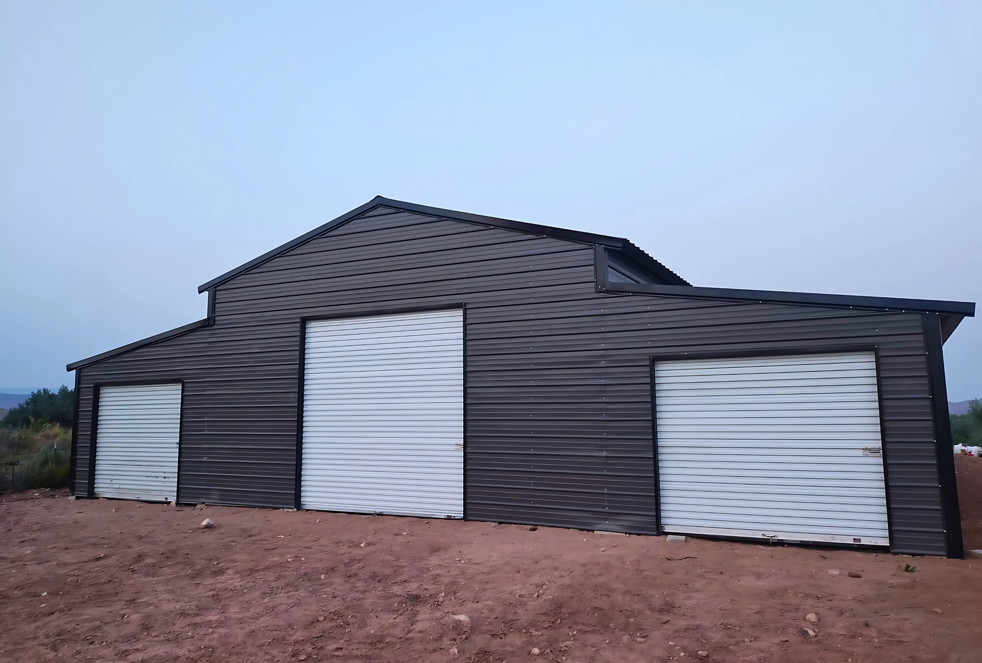 Front right view of 48' x 100' steel barn with lean-tos, and garage doors for livestock or farm equipment storage.