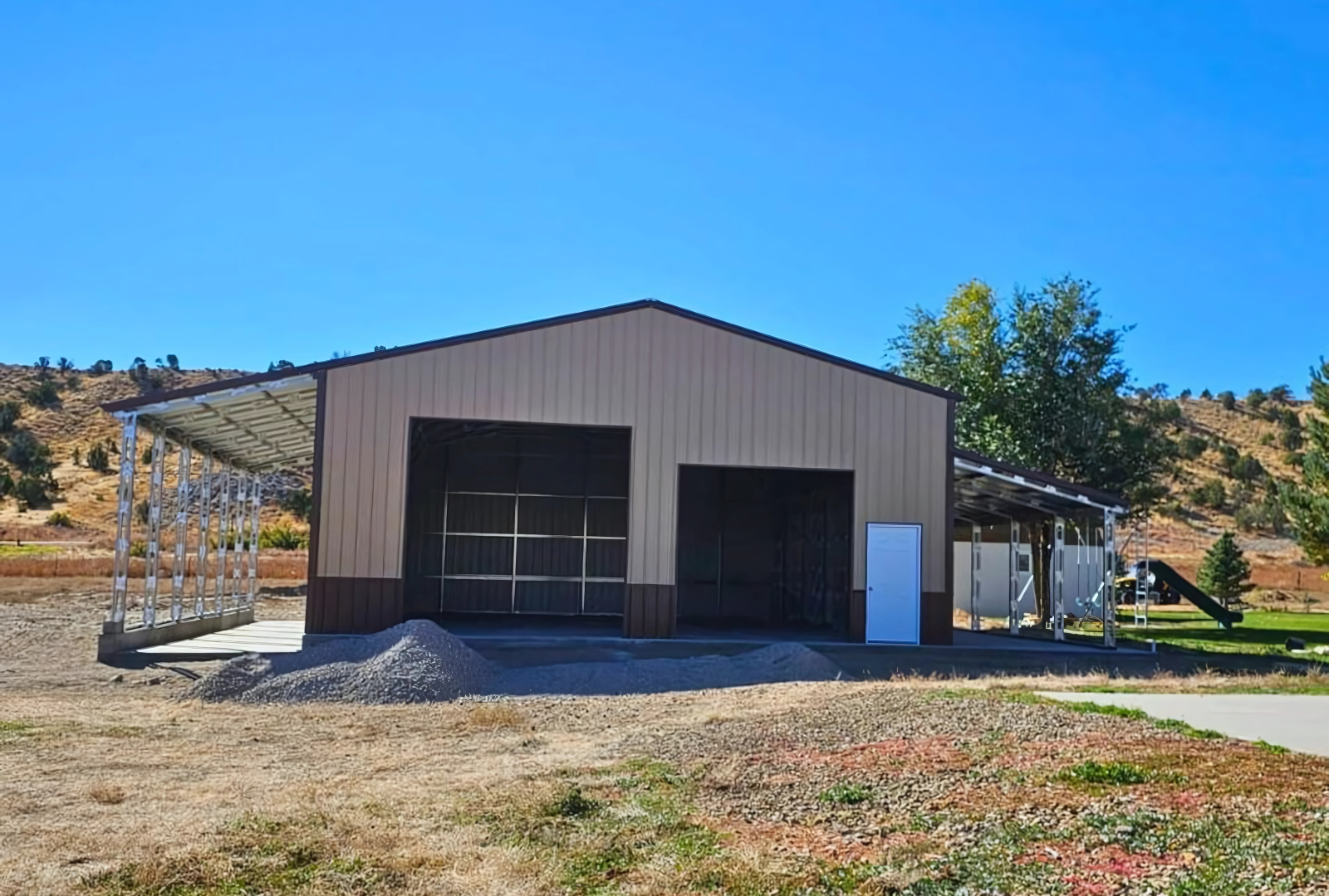 56'x45'x14' metal building with main section 36'W x 45'L x 14'H, left lean-to 10'W x 45'L x 14'-11'6"H, right lean-to 10'W x 45'L x 10'-7'6"H. Features web truss design, vertical roof, 14 Ga. frame, 40PSF ground snow load, fully enclosed with vertical siding, one 36" x 80" walk-in door, and frame outs for one 12' x 12' and one 10' x 10' overhead doors on the front end. Includes 150 1/2" concrete bolts.