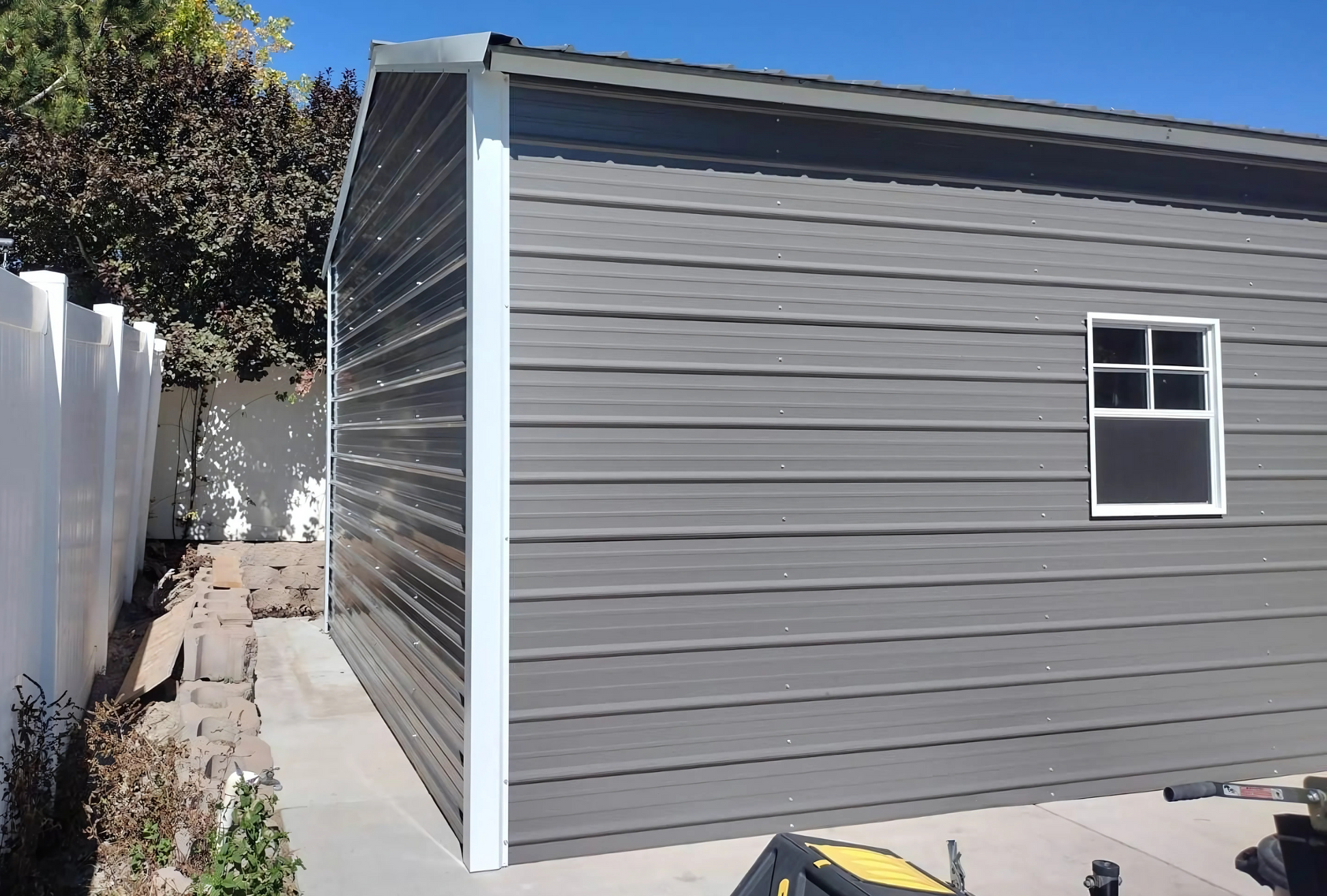 Outside left angle rear view 18'x25'x10' f-frame vertical roof building with roll-up door, walk-in door, and window.