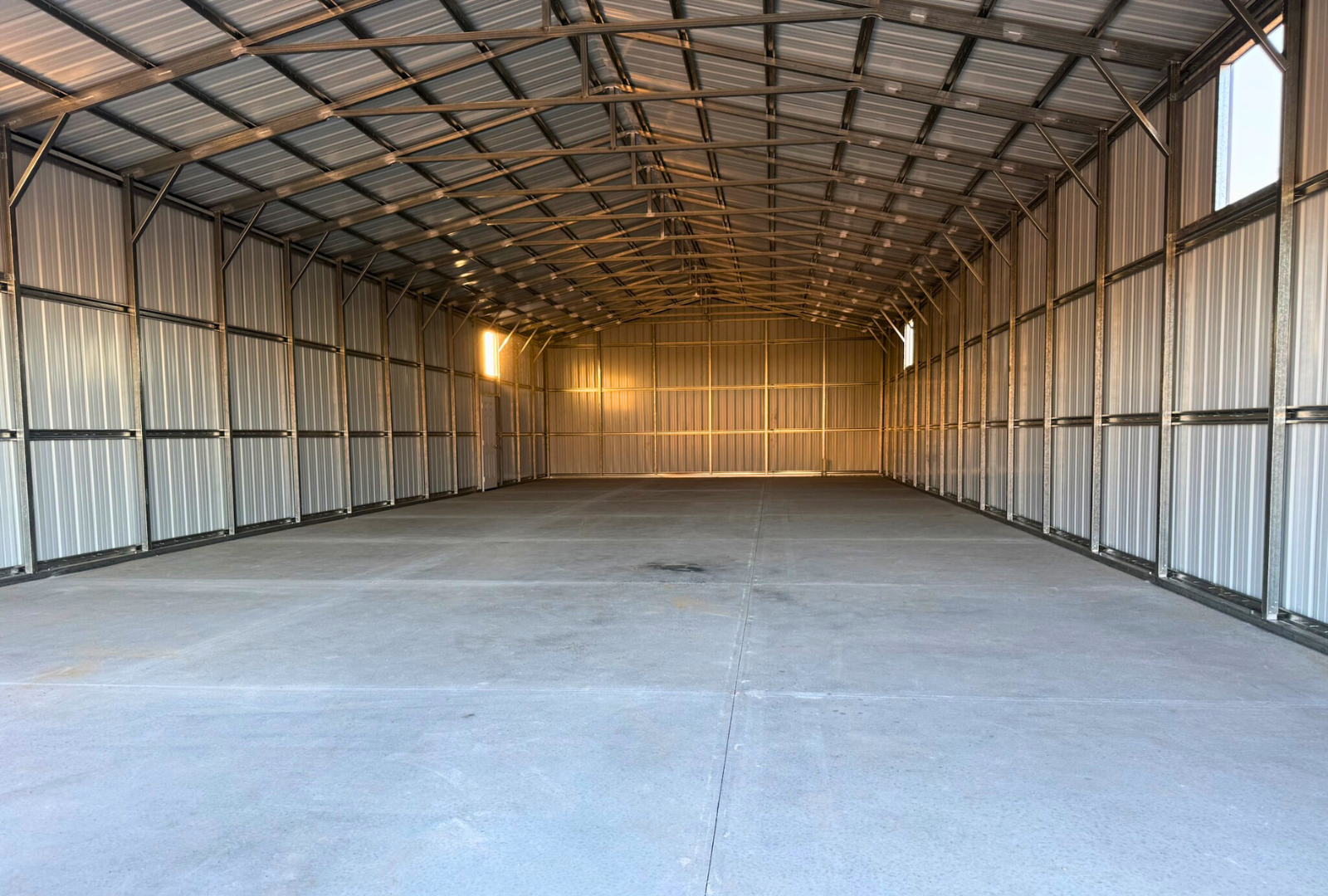 Inside front view of a 30x80 A-frame steel building by Alpha Steel Buildings, showing the interior framing and multiple window frame outs for a spacious metal workshop layout.